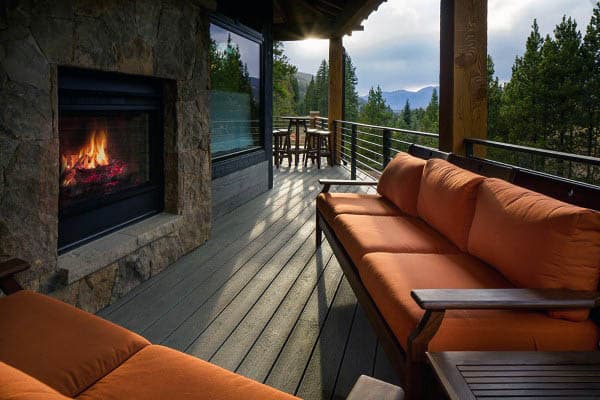 Cozy outdoor patio with orange sofas, a fireplace, and a scenic mountain view