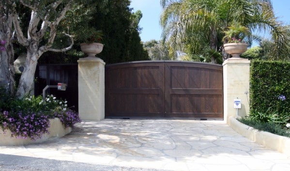 Dark wood driveway gate with a smooth, slightly arched top and a seamless panel design for a classic, elegant look.