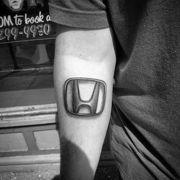 Realistic Honda logo tattoo on a man's forearm, featuring bold shading and a three-dimensional effect for a standout design.