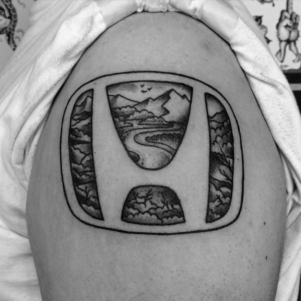 Honda logo tattoo on a man's upper arm, featuring a detailed nature scene inside the emblem with mountains, trees, and a winding river.
