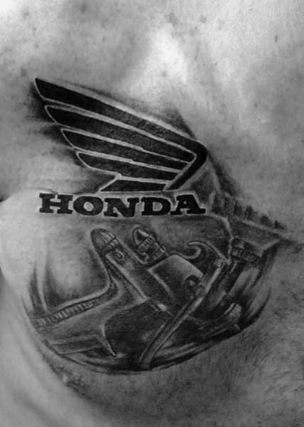 Honda wing logo tattoo on a man's chest, featuring bold black lettering with detailed mechanical tools below for a rugged, industrial look.