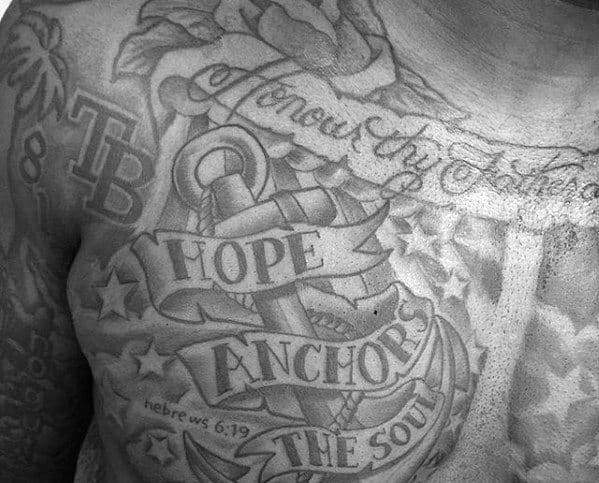 Chest tattoo with anchor, intricate text, and decorative elements