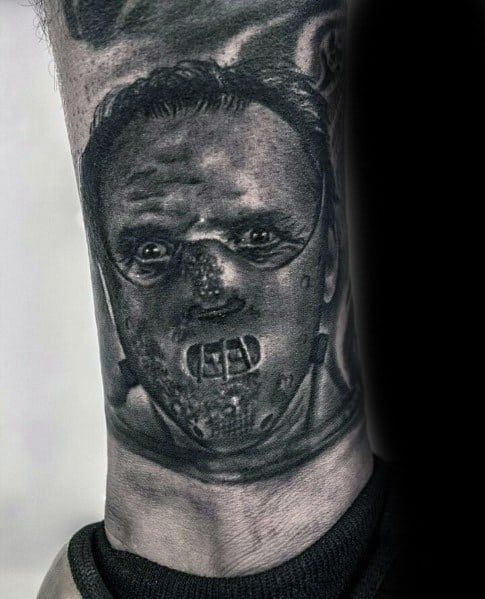 Realistic black and grey tattoo of Hannibal Lecter from *The Silence of the Lambs*, featuring his iconic muzzle and intense shading for a chilling effect.