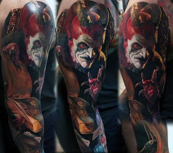 Color tattoo of a sinister jester with red and white face paint, sharp features, and eerie shading, creating a dark and haunting horror aesthetic.