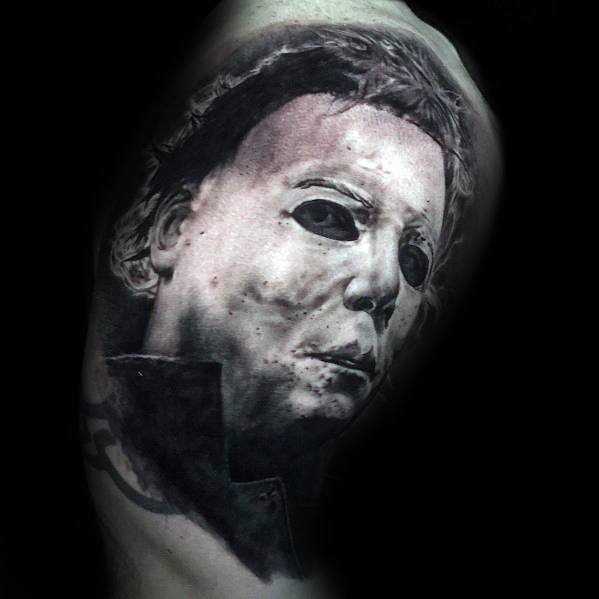 Black and grey tattoo of Michael Myers from *Halloween*, featuring his eerie white mask, dark eyes, and detailed shading for a chilling effect.