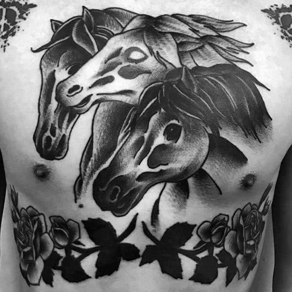 Black and grey chest tattoo of three horse heads with bold shading, framed by roses and leaves along the bottom