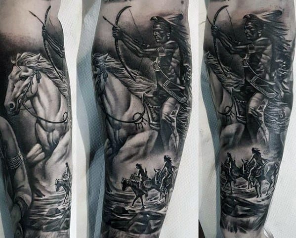 Black and grey tattoo sleeve of a Native American warrior on horseback aiming a bow, with additional horse riders and scenic elements below
