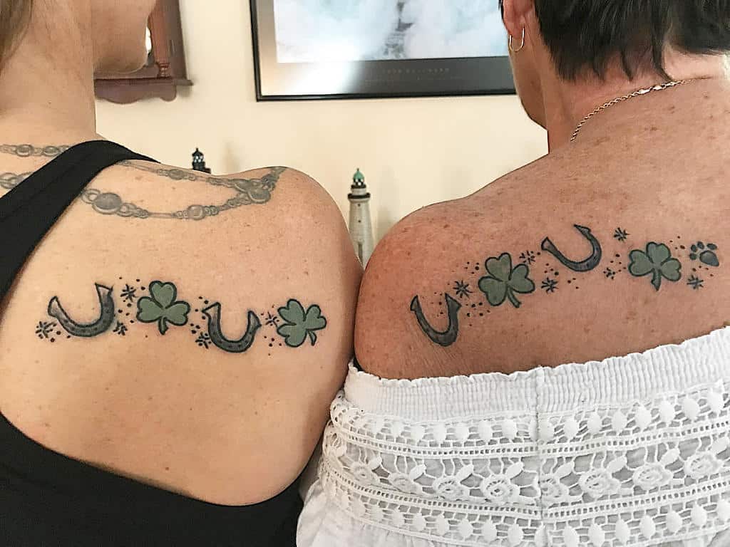 Matching mother-daughter tattoos featuring horseshoes, shamrocks, and stars symbolizing luck, love, and a special bond.