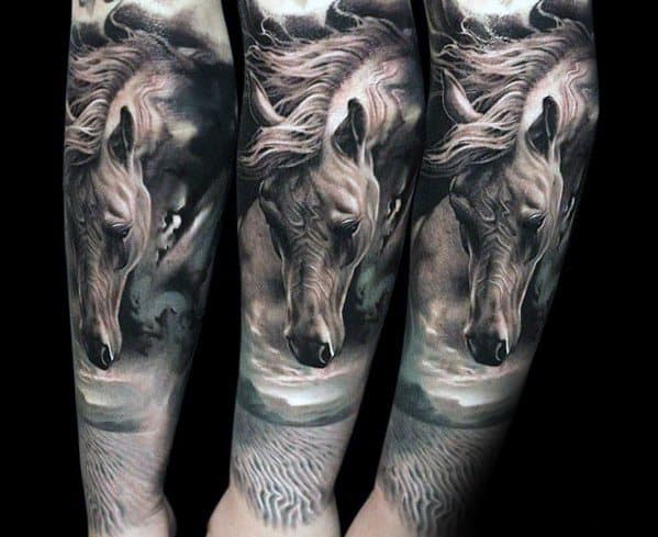 Realistic black and grey horse head tattoo on the forearm, with flowing mane and detailed cloudy sky background