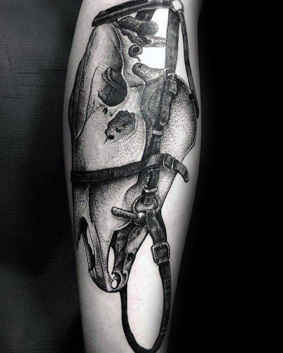Detailed blackwork tattoo of a horse skull in a halter, placed on the calf, with bold dotwork shading and anatomical precision