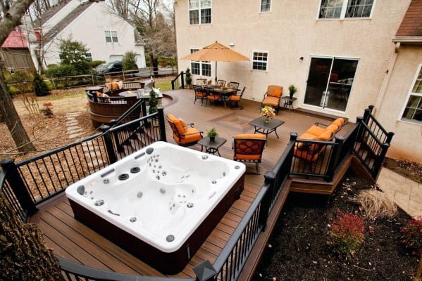 large backyard wood deck metal fencing and rail hot tub outdoor furniture with orange cushions