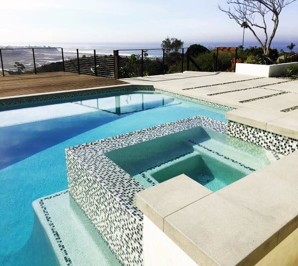A modern pool and hot tub with sleek black-and-white mosaic tiles and stunning ocean views.