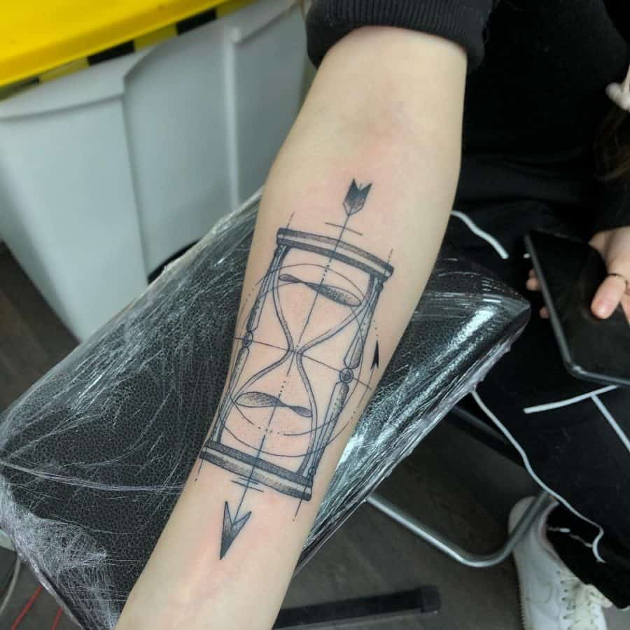 Forearm tattoo of a geometric hourglass pierced by arrows, symbolizing the passage of time with fine line details and modern minimalist design.
