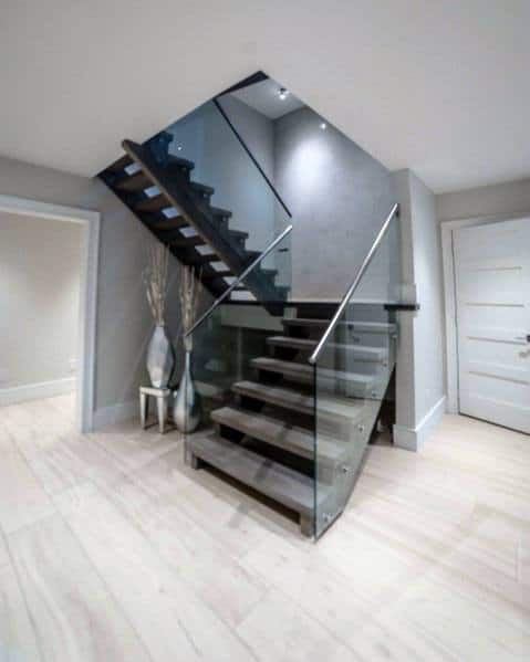 U-shaped staircase with dark wooden steps and glass railing in a sleek modern interior.