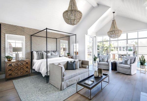 Spacious farmhouse bedroom with a canopy bed, sofa, armchairs, large windows, and neutral tones