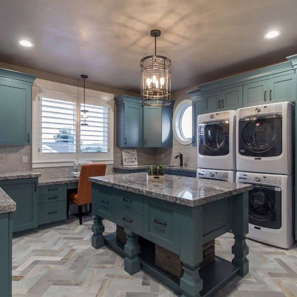 Spacious laundry room with teal cabinets, granite countertops, and stacked washer-dryer units.