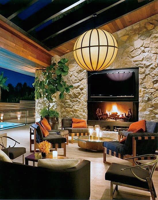 Cozy living room with a lit fireplace, seating, a large globe light, and a view of a pool outside