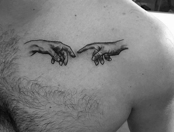 A tattoo of two hands reaching towards each other on a person's chest