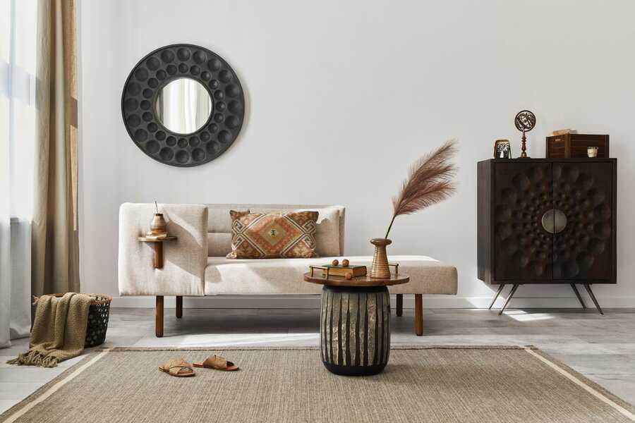 Textured round mirror above a neutral sofa, paired with a sculpted cabinet, natural decor, and earthy tones for a warm, modern look.