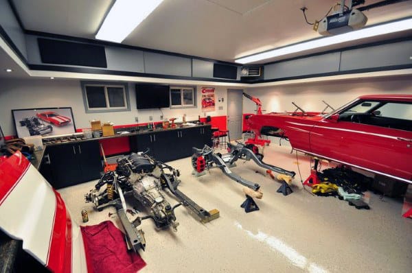 Garage showcasing a classic car restoration in progress with tools and red cabinets amidst the disassembled auto