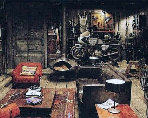 Cozy room with a garage flair, featuring a motorcycle, sofas, a table, books, and a unique hanging fireplace