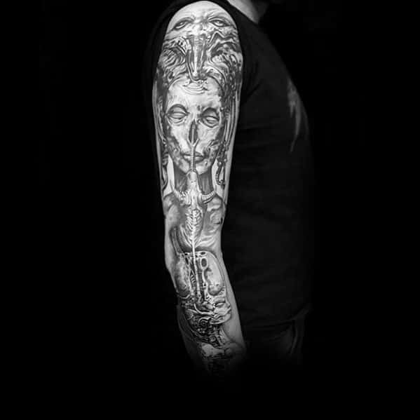 Full-sleeve HR Giger-style tattoo featuring a haunting biomechanical female face merged with surreal alien and mechanical elements.