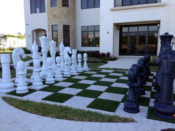Backyard with a life-sized chess board featuring large black and white chess pieces.