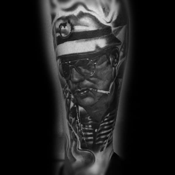 Black and white Hunter S. Thompson tattoo featuring a detailed portrait with aviator glasses, a cigarette, and a military-style hat with bold shading.