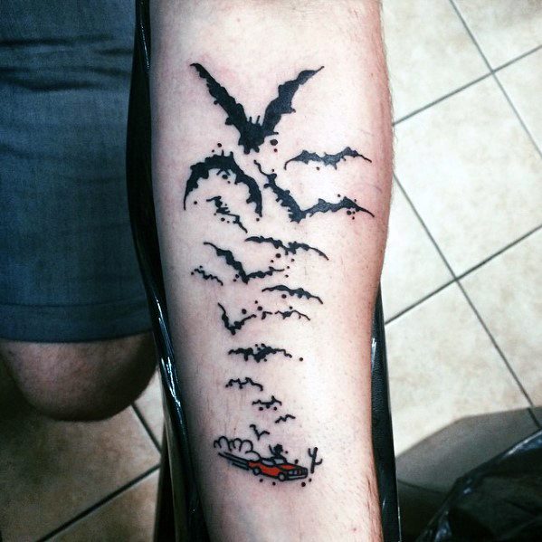 Minimalist Hunter S. Thompson tattoo featuring a small red car driving through the desert with bats forming a larger bat shape above it.