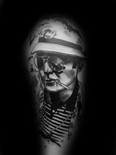 Black and white Hunter S. Thompson tattoo featuring a detailed portrait with aviator glasses, a bucket hat with a skull emblem, a cigarette, and bold shading.