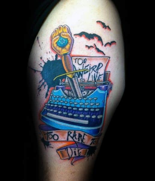 Colorful Hunter S. Thompson-inspired tattoo featuring a blue typewriter, a fist holding a peyote button, bats, and the quote "Too weird to live, too rare to die."