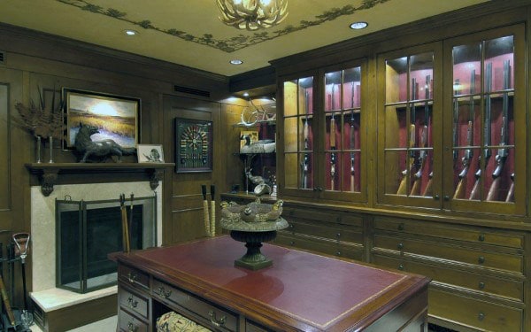 Hunter's room with wood cabinets, fireplace, and elegant glass gun displays.