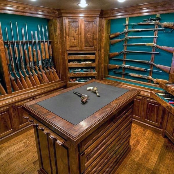 Sophisticated gun room with rich wooden cabinets, teal walls, and a central island for showcasing firearms.