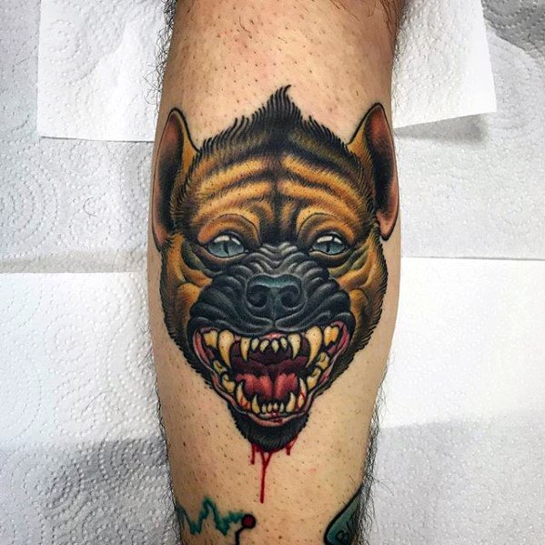 Neo-traditional hyena head tattoo on the calf with bold shading, sharp teeth, blood detail, and intense eyes for a striking and fierce look.