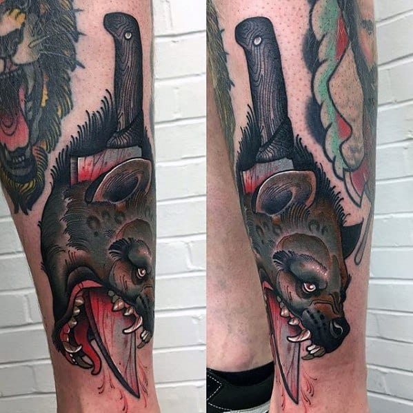 Neo-traditional hyena tattoo with a cleaver embedded in its head, bold outlines, blood details, and fierce expression on the lower leg.