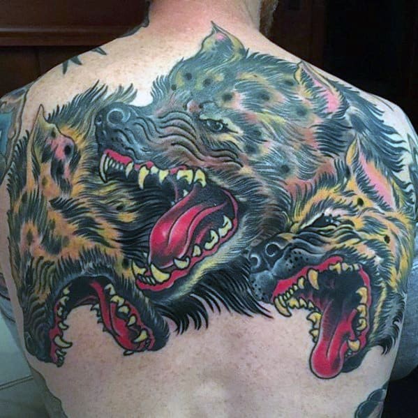 Vibrant back tattoo of a three-headed hyena with snarling expressions, exaggerated tongues, and bold traditional-style colors and outlines.
