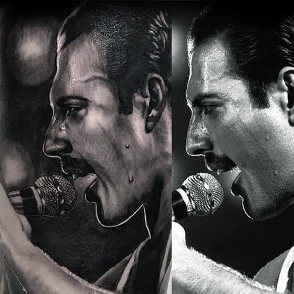Hyper-realistic black and grey tattoo of Freddie Mercury singing into a microphone, capturing sweat details and intense stage focus.