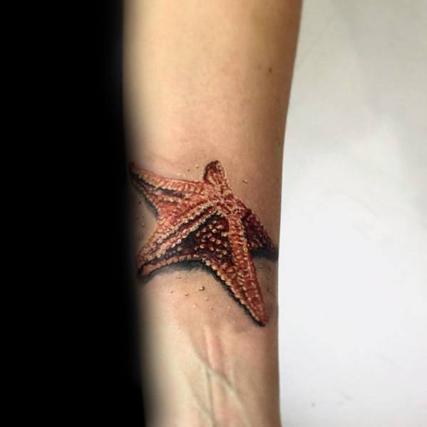 Realistic orange starfish tattoo on the inner forearm with detailed texture and shading, giving it a 3D appearance.