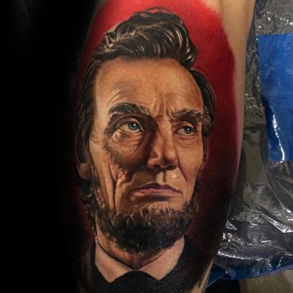 Realistic tattoo of a bearded Abraham Lincoln in a suit on skin, with a red background