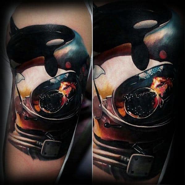 Intricate black and colorful tattoo on the upper arm, depicting an orca whale inside a diver's helmet, with a dramatic and surreal underwater effect created by vivid details and shading.