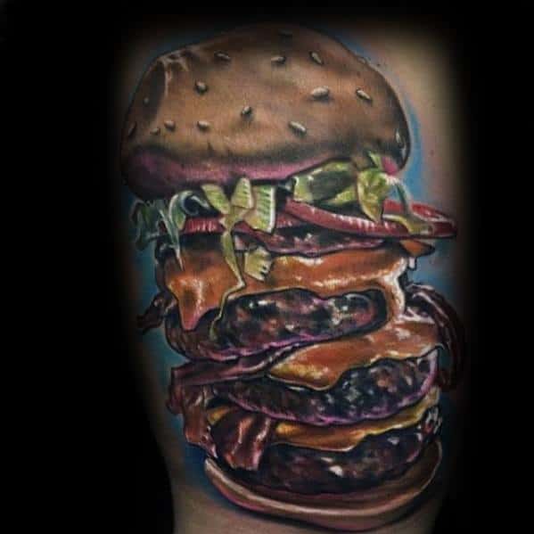 Tattoo of a towering cheeseburger masterpiece with multiple patties, lettuce, and toppings on a dark background