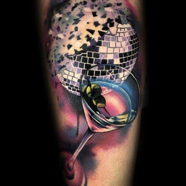 Vibrant tattoo of a shattered disco ball with a martini glass, blending nightlife and party vibes with bold colors and dynamic shading.