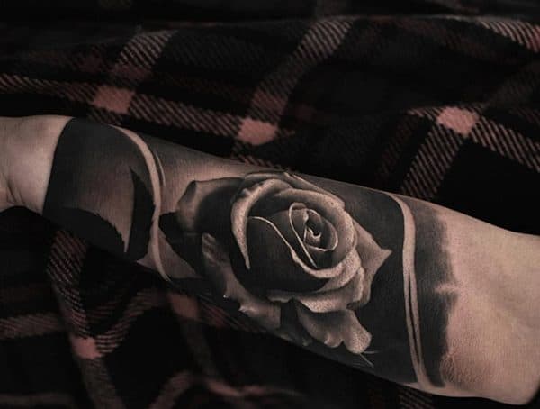 Black and grey realism tattoo of a rose on the forearm, featuring intricate shading and depth for a lifelike floral design.