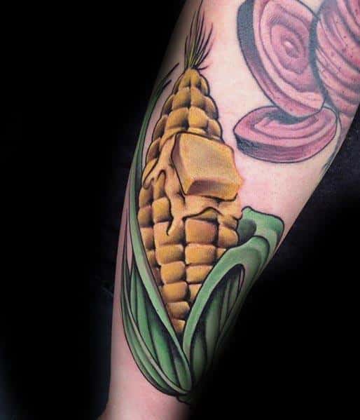 Bold tattoo of a detailed corn cob with melting butter on top, featuring rich shading and vibrant colors for a realistic look.
