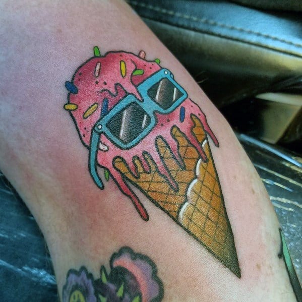Tattoo of a melting pink ice cream cone with sprinkles, wearing blue sunglasses, blending fun and quirky elements with bold outlines and shading.
