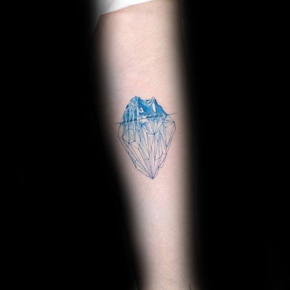 Delicate blue iceberg tattoo with fine line detailing and soft shading, showing the larger submerged section below the waterline.