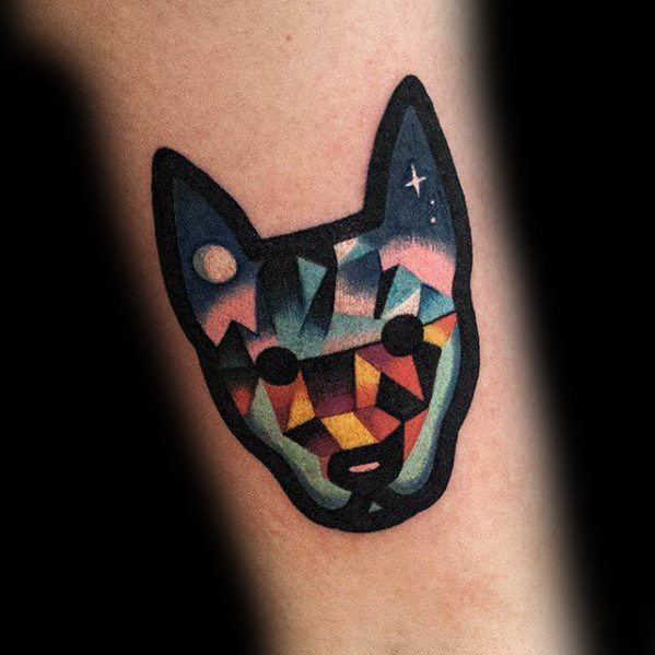 Vibrant geometric tattoo of a cat's face with bold colors, starry sky elements, and abstract polygonal patterns.
