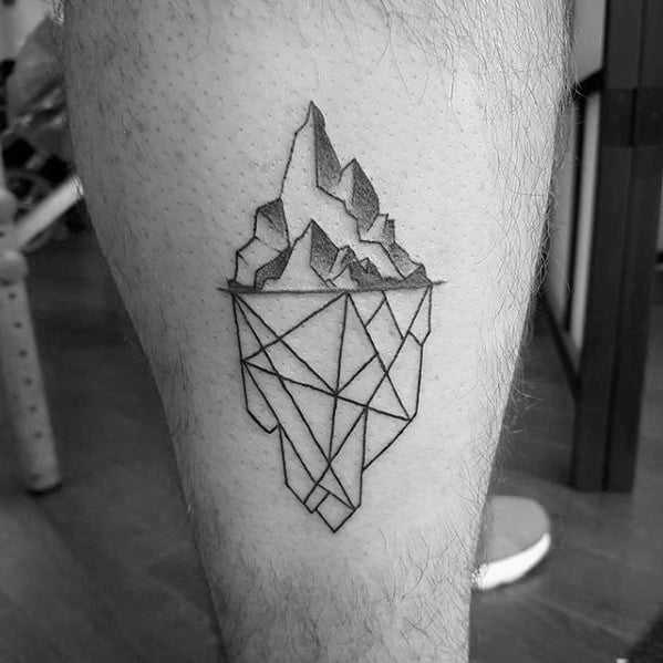 Geometric iceberg tattoo on the leg with sharp linework, combining realistic peaks above and angular shapes below the waterline.