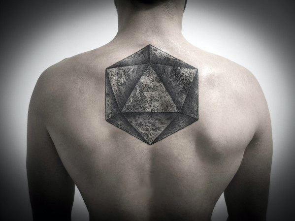 Large icosahedron tattoo centered on upper back with textured shading and a stone-like, dimensional appearance.