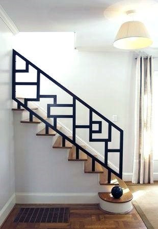 Staircase with custom black ornate metal handrail and wooden steps in a bright modern home.